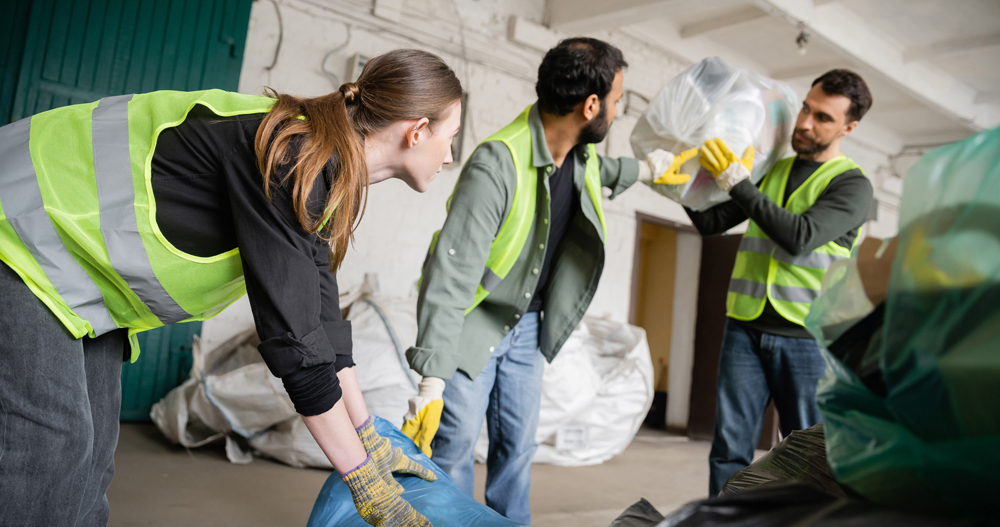 Young female worker in protective vest and gloves holding plasti